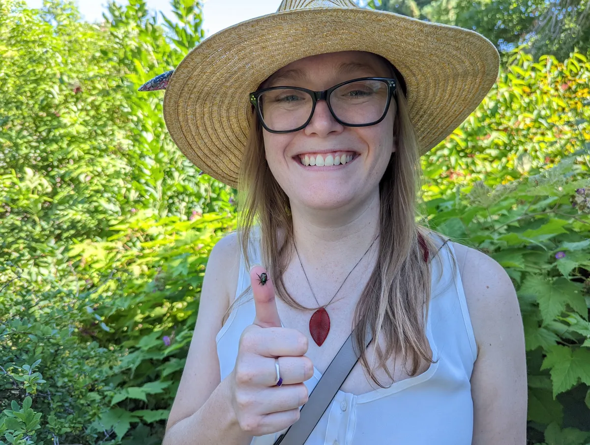 Maia in a garden with a green bottle fly on her thumb
